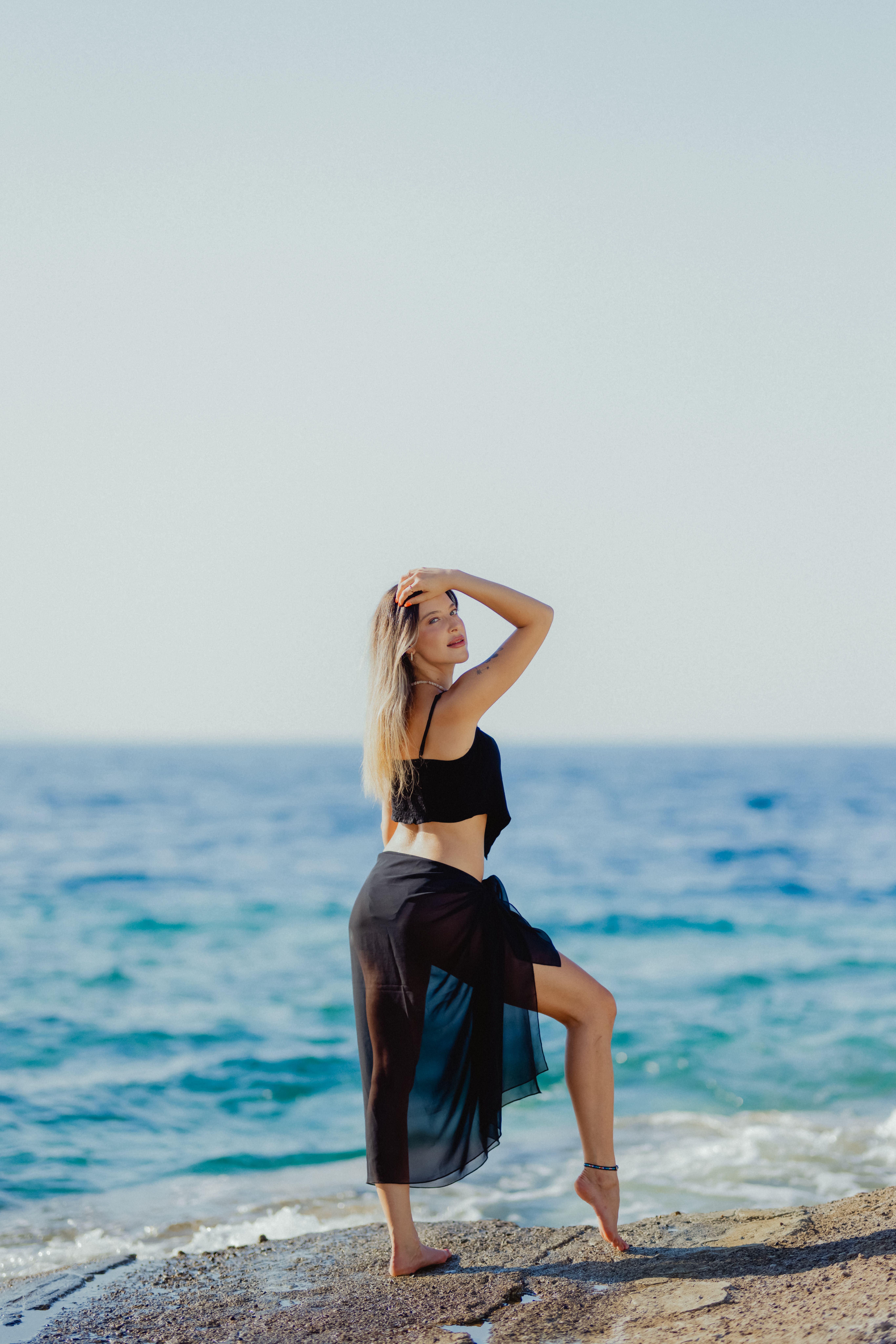 A woman in a black dress is standing on the beach · Free Stock Photo