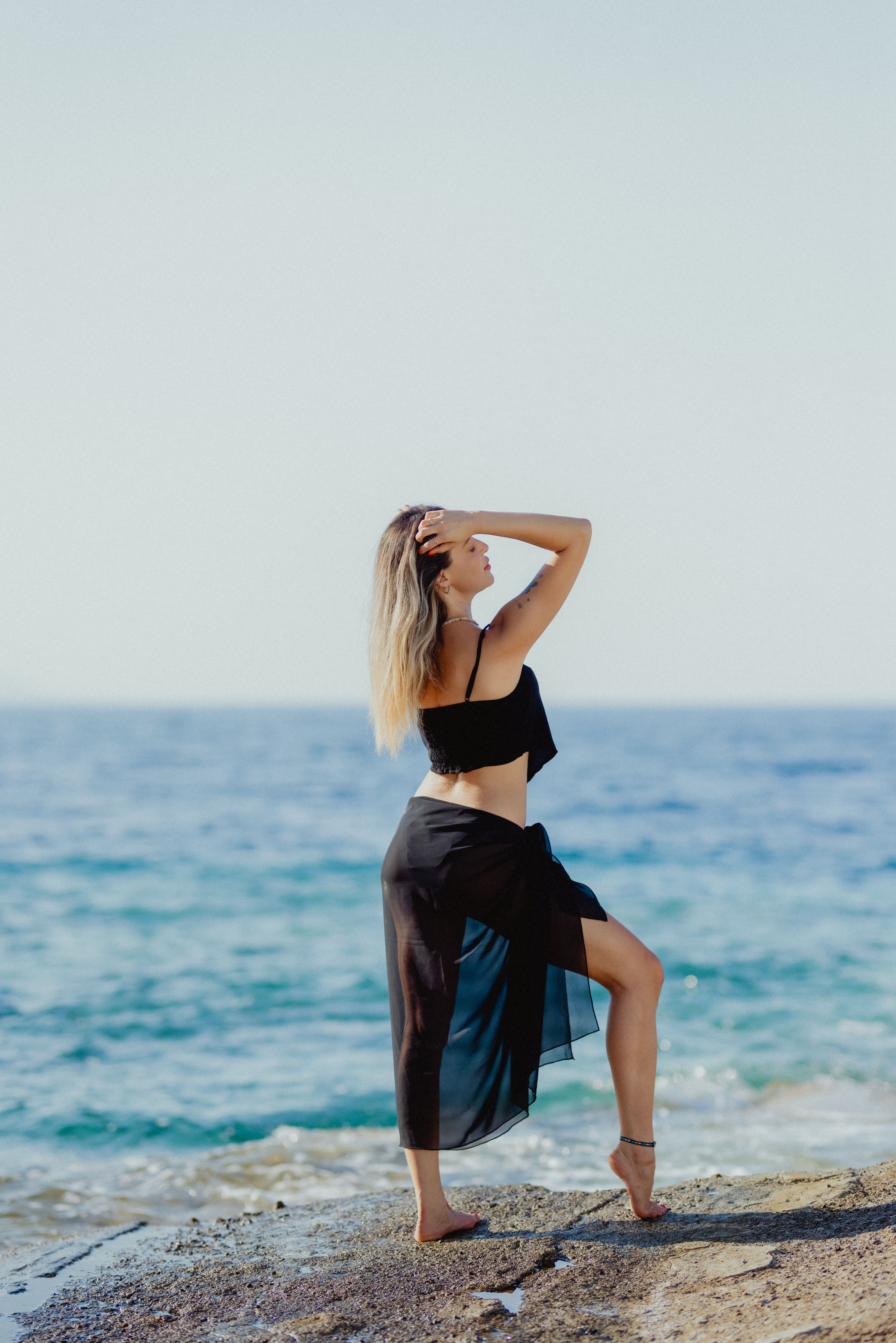 A woman in a black dress is standing on the beach · Free Stock Photo