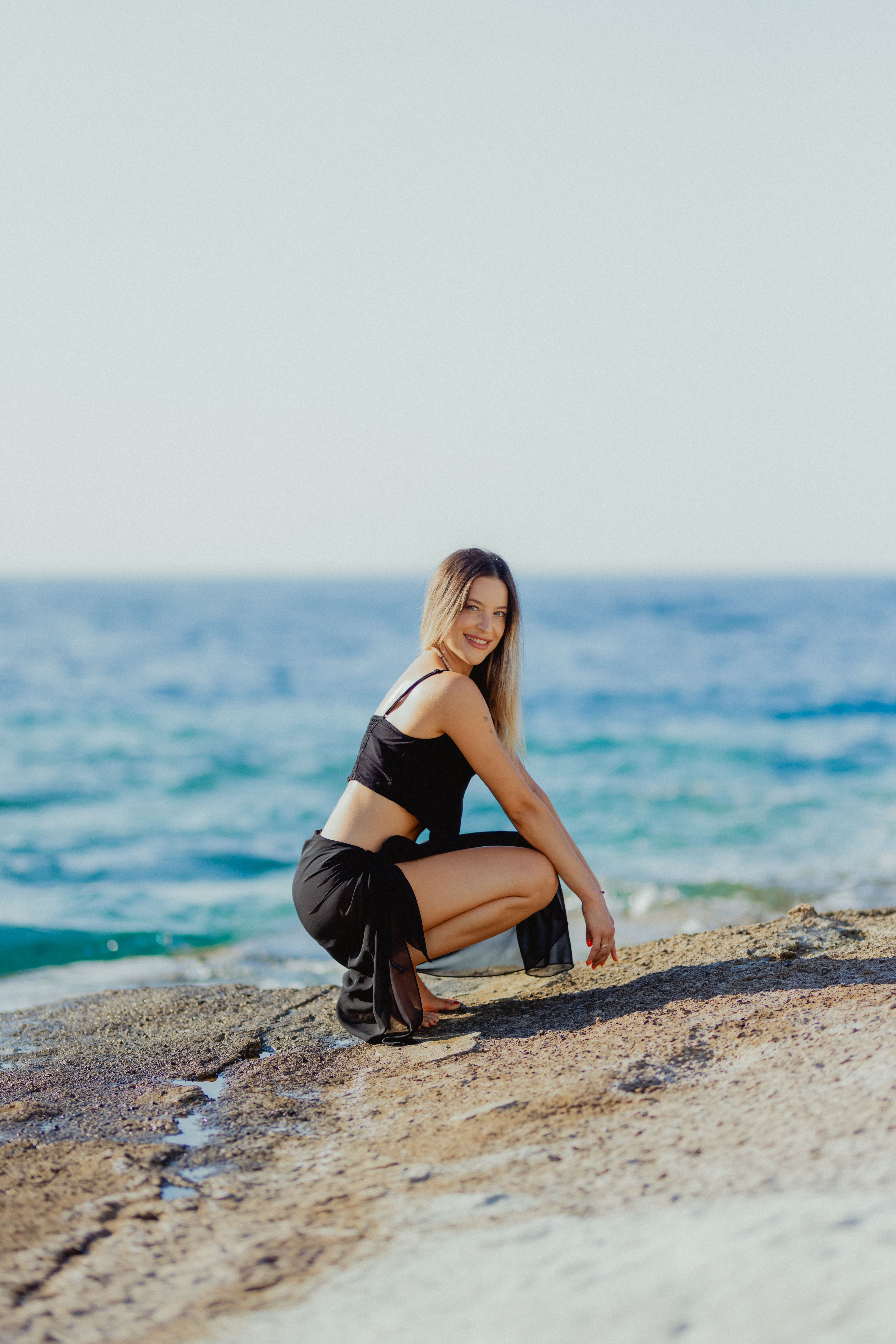 A woman in a black dress sitting on the beach · Free Stock Photo