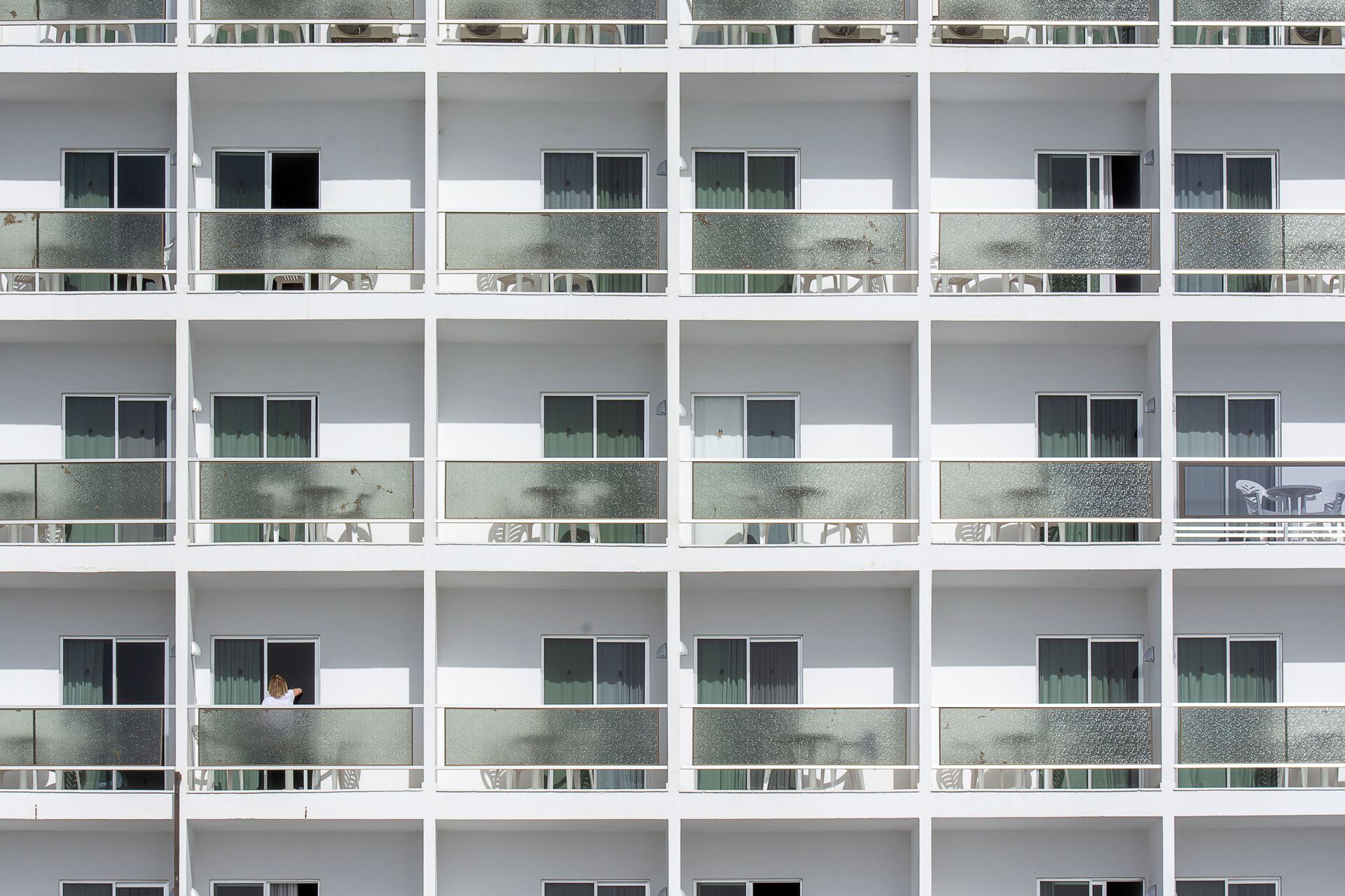 Symmetrical facade of modern apartments featuring sliding glass doors and balconies.