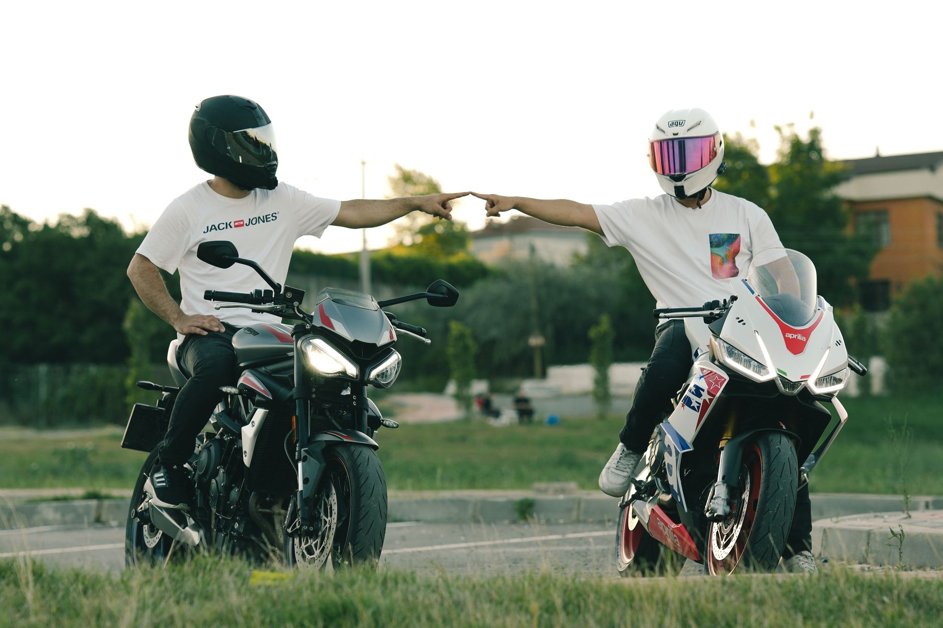 Two bikers exchanging a fist bump while sitting on their motorcycles outdoors.