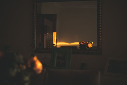 Free A warm and inviting interior room with a glowing mirror reflection at dusk. Stock Photo
