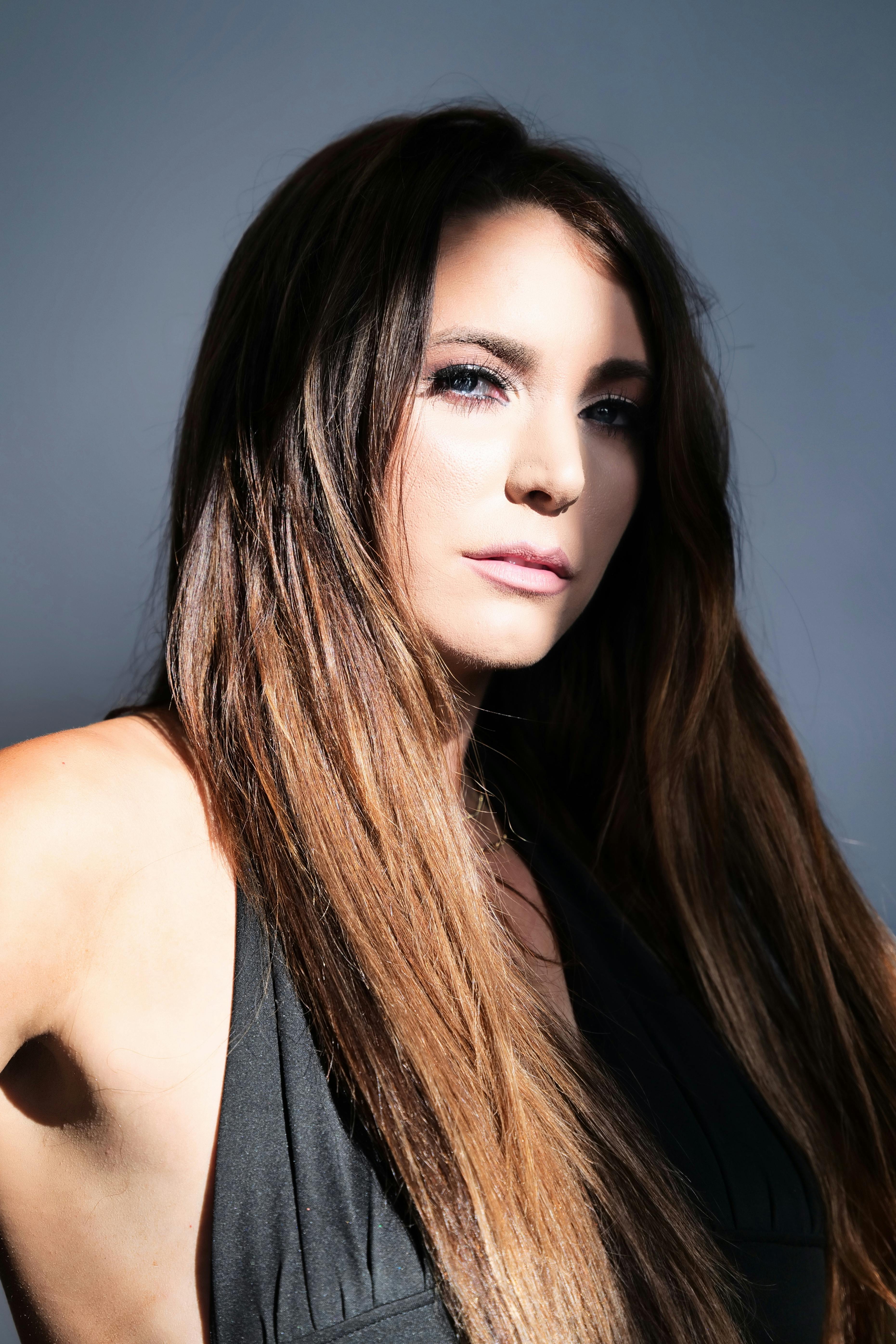 Captivating portrait of a young brunette woman with long sleek hair in studio lighting.