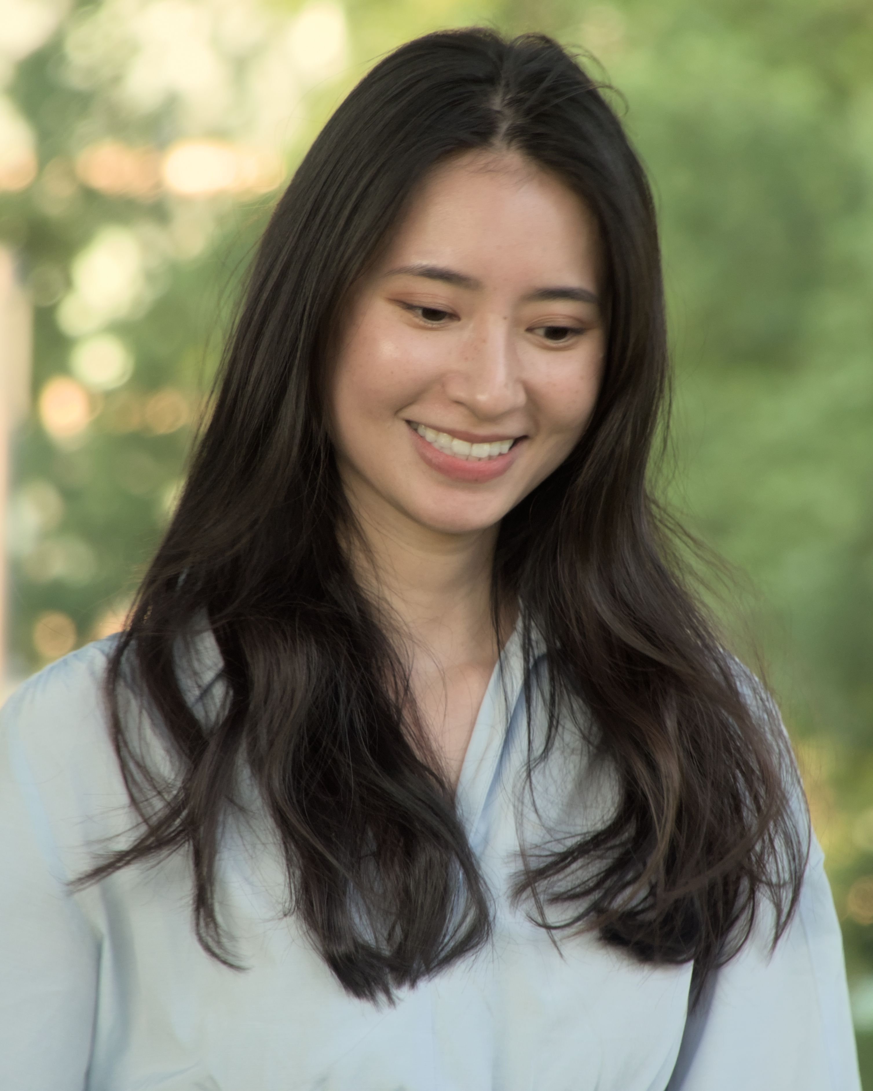 Smiling young woman with long hair enjoying a sunny day outdoors in Berlin.