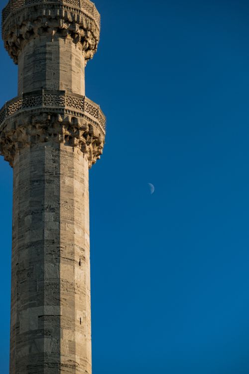 Free Stunning view of a traditional minaret silhouetted against a deep blue sky with a crescent moon, capturing serene spirituality. Stock Photo