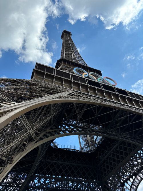Free View of the Eiffel Tower adorned with Olympic rings, symbolizing global unity. Perfect for travel and architecture enthusiasts. Stock Photo