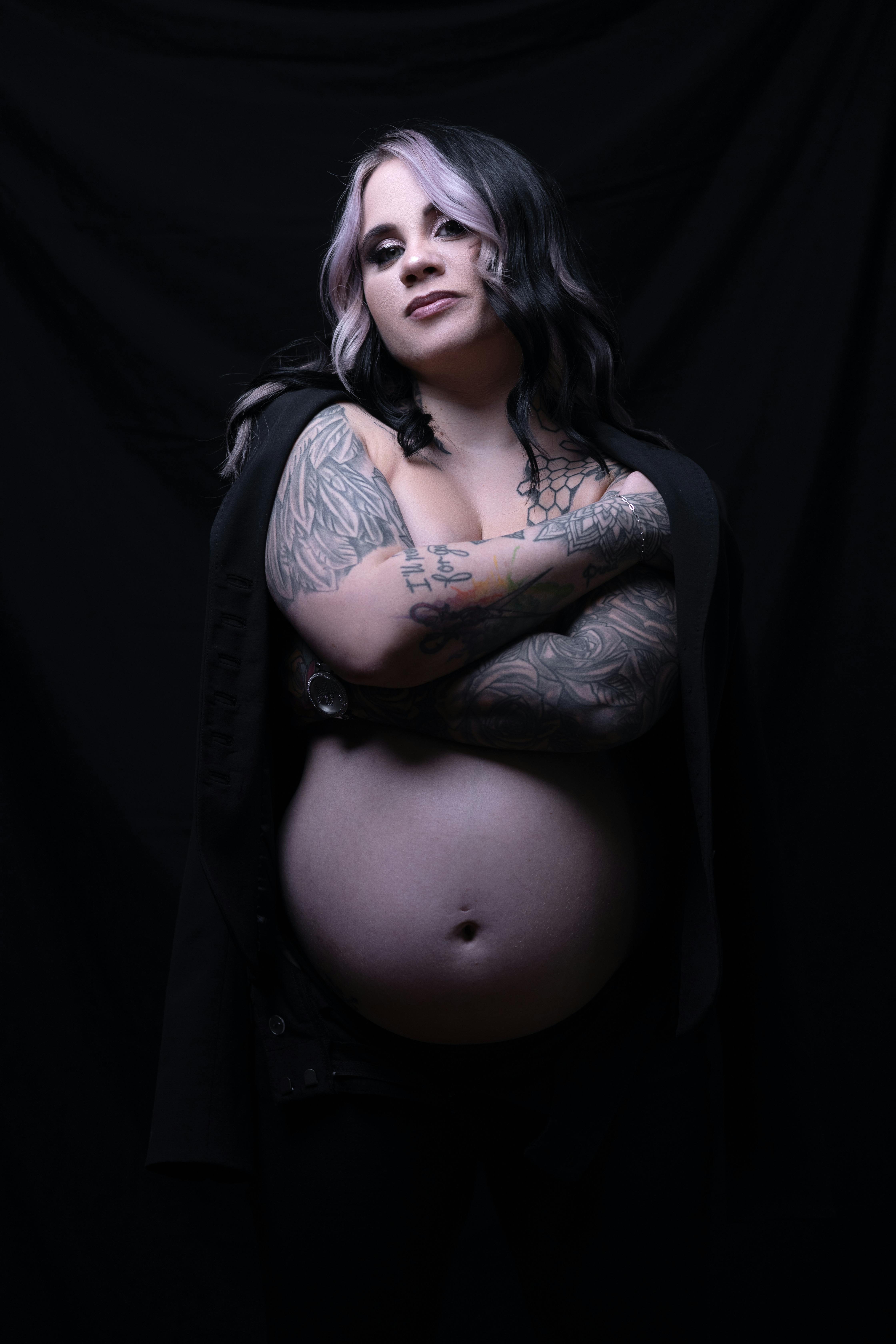 a pregnant woman with tattoos on her arms