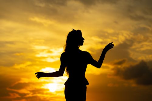 Free Silhouette of a woman dancing gracefully against a vibrant sunset sky. Stock Photo