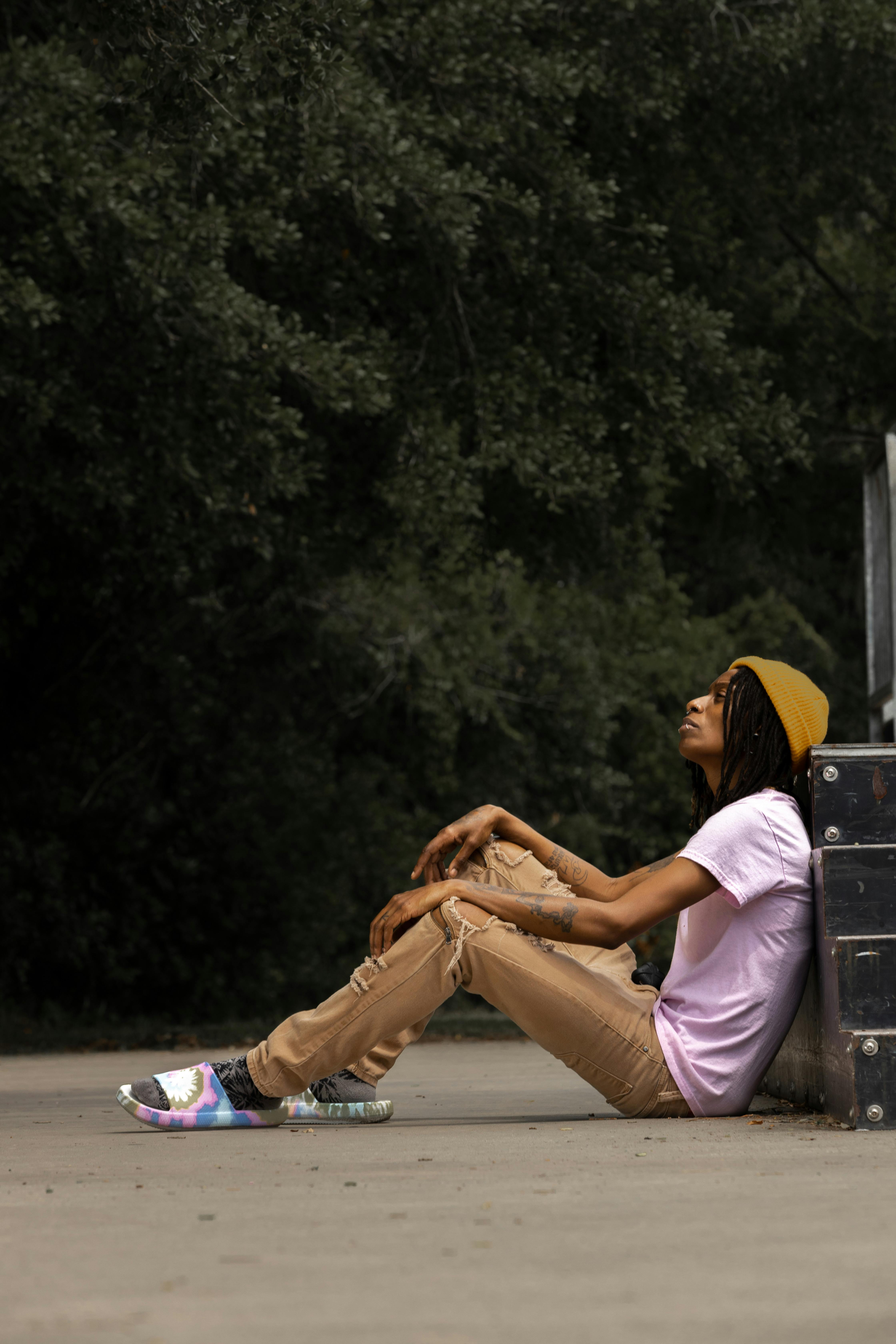 a young man sitting on the ground with his skateboard