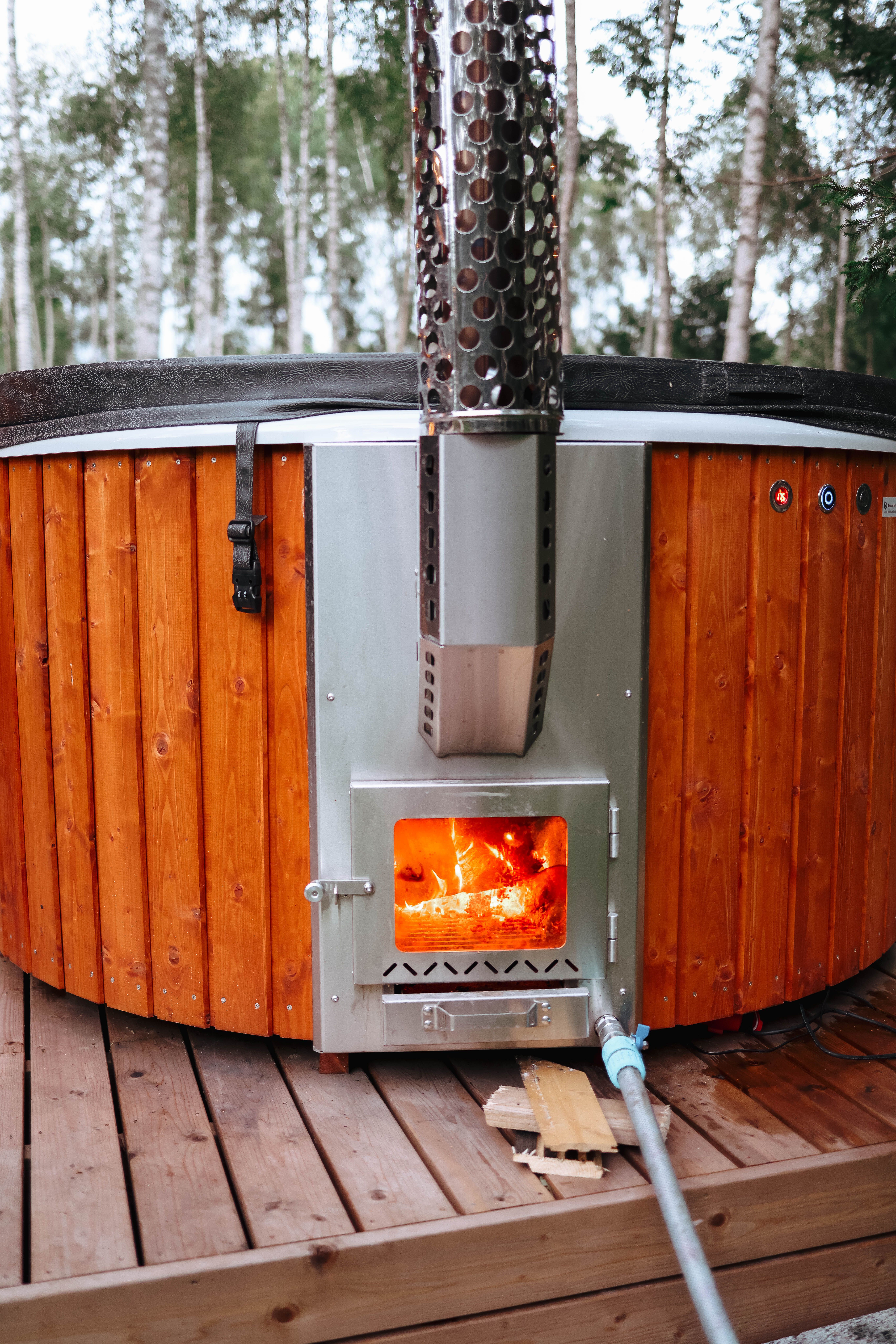 Rustic outdoor hot tub heated with wood fire, surrounded by nature. Ideal for relaxation.