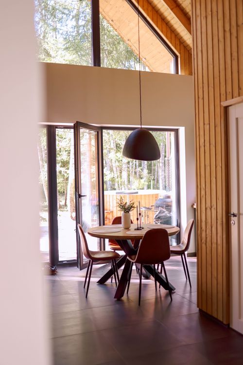 Free Stylish dining room with wooden decor and large windows overlooking outdoors. Stock Photo