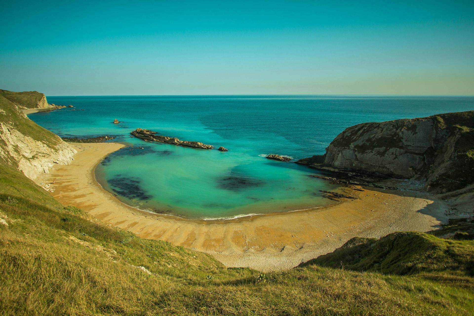 Beautiful beach cove with clear turquoise waters and rocky cliffs, perfect for summer relaxation.