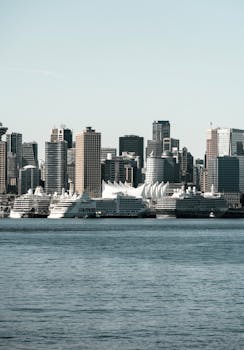 A scenic view of Vancouver's skyline with multiple cruise ships docked, showcasing urban beauty.