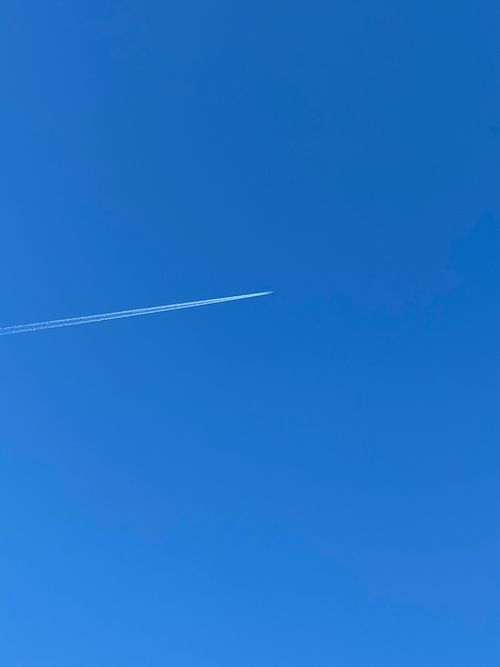 Free A jet airplane leaves a white contrail across a vast, clear blue sky. Ideal travel imagery. Stock Photo