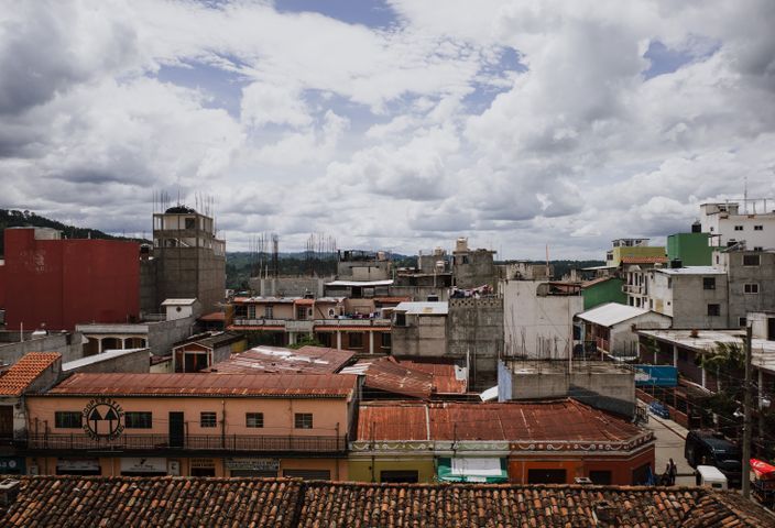 A vibrant urban cityscape showcasing colorful rooftops in Chichicastenango, Guatemala with dramatic clouds above.
