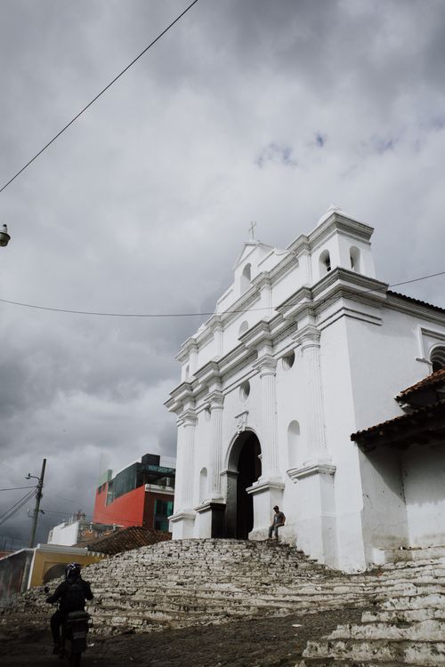 Free White colonial church with cloudy backdrop in Chichicastenango, Guatemala, showcasing local culture and architecture. Stock Photo
