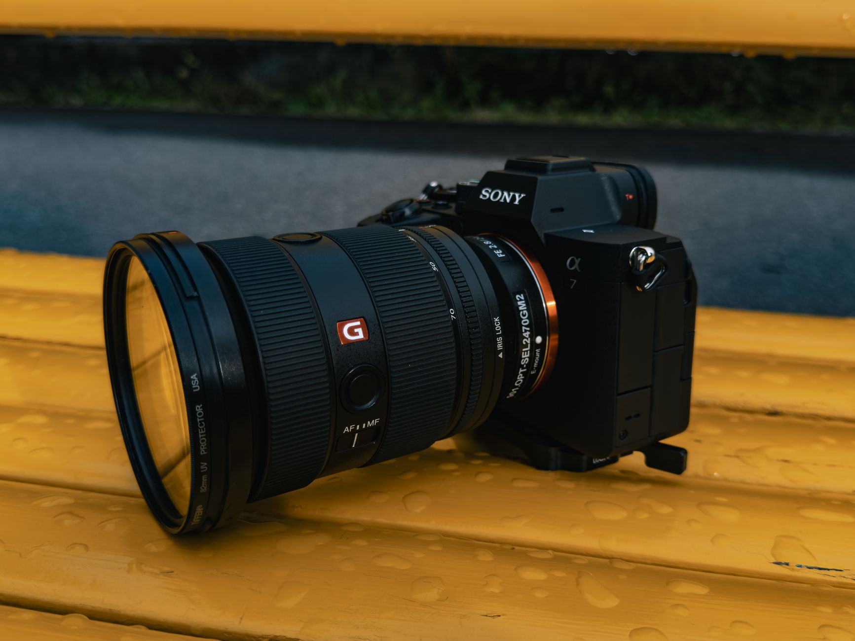 A DSLR camera with a large lens resting on a wet yellow bench, showcasing photography gear essentials.
