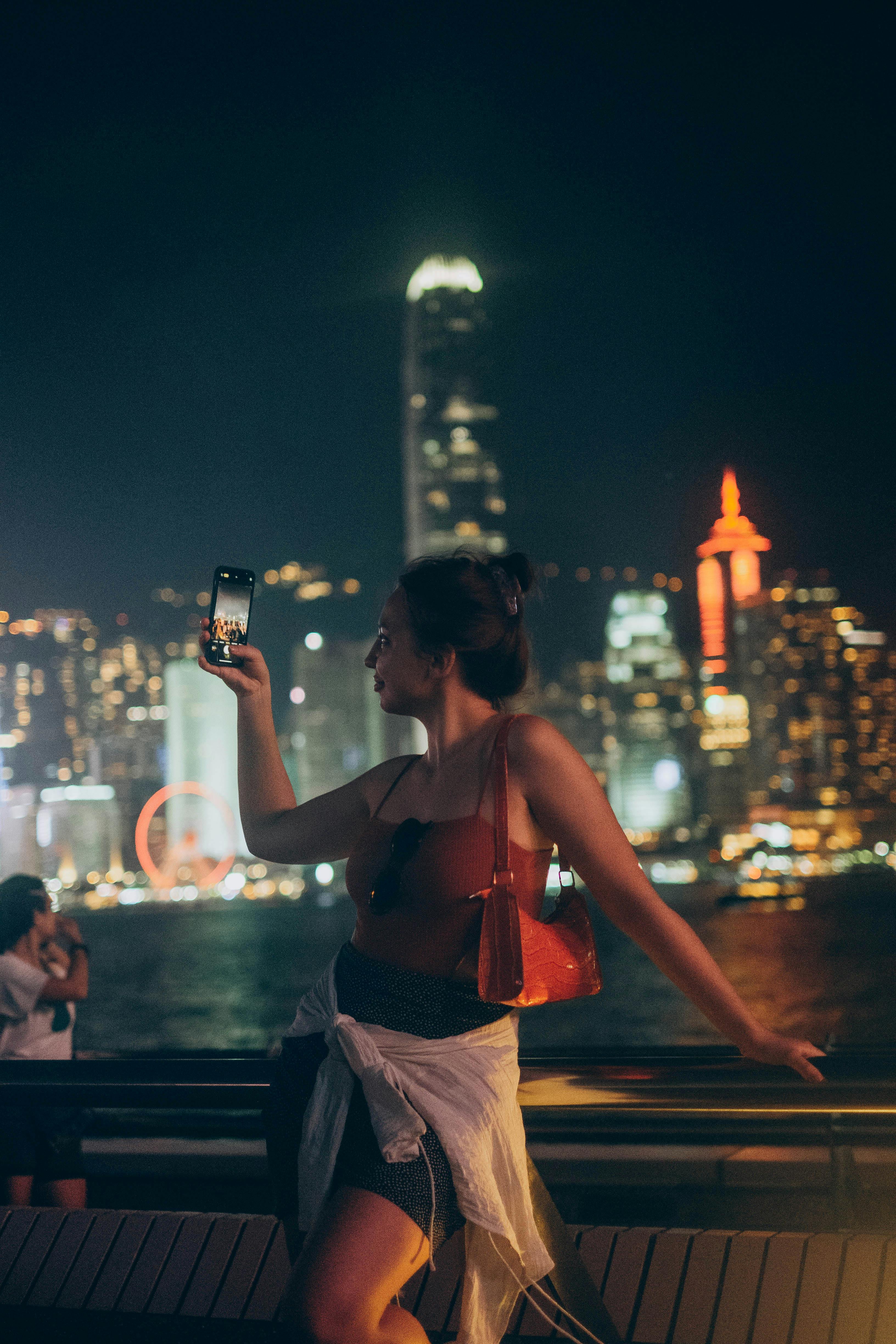 Solo female traveller walking along the Marina Bay waterfront at night with the illuminated Singapore skyline in the background