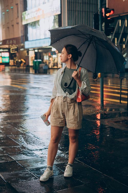 Free Woman standing on wet urban street with umbrella in rainy Hong Kong night. Stock Photo