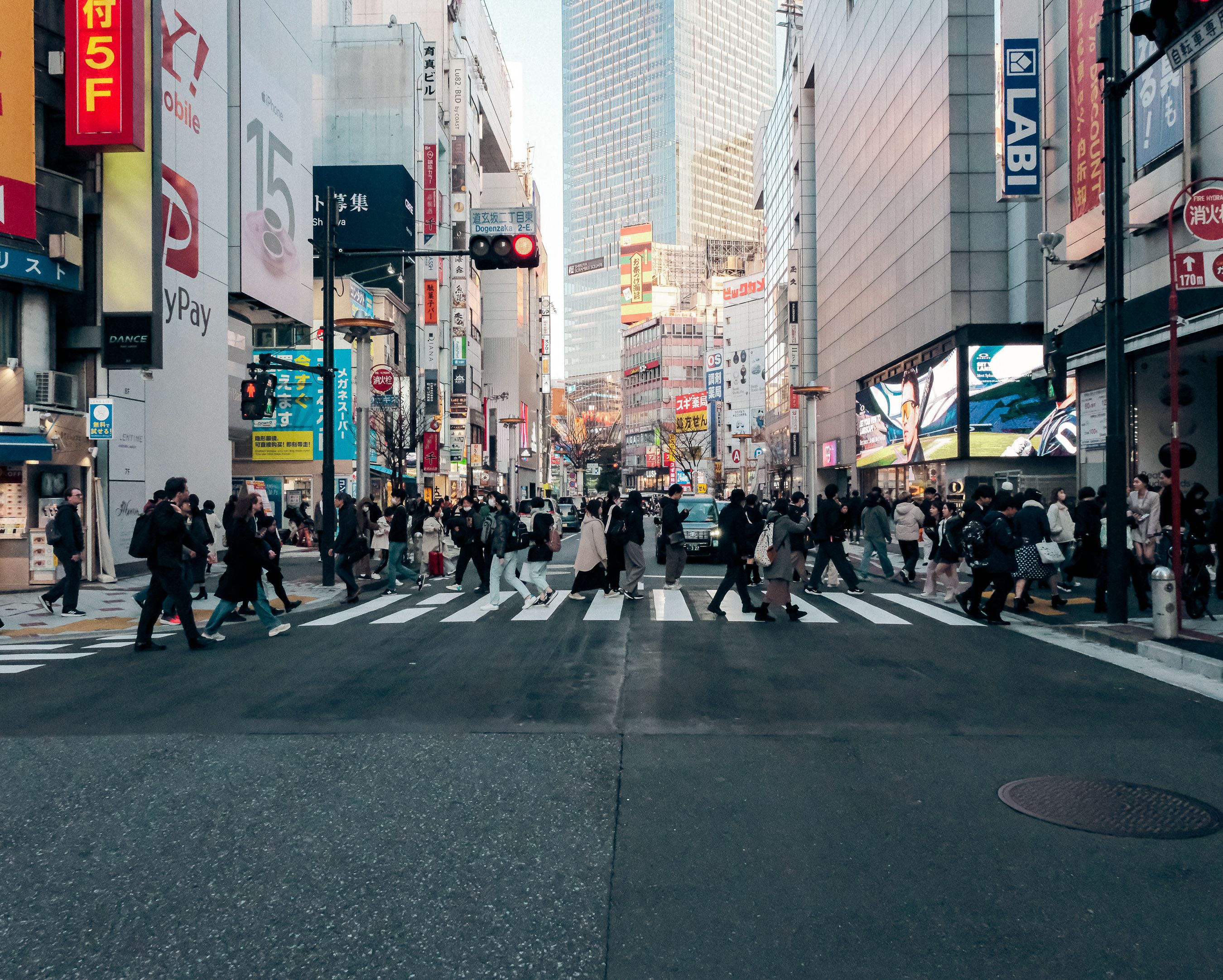 Multitudes cruzando la intersección de Shibuya en Tokio, Japón, durante la noche con luces vibrantes de la ciudad.