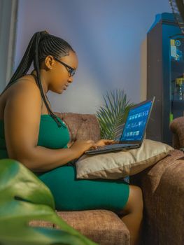 Young woman in green dress working on a laptop in a cozy indoor setting, sitting comfortably.