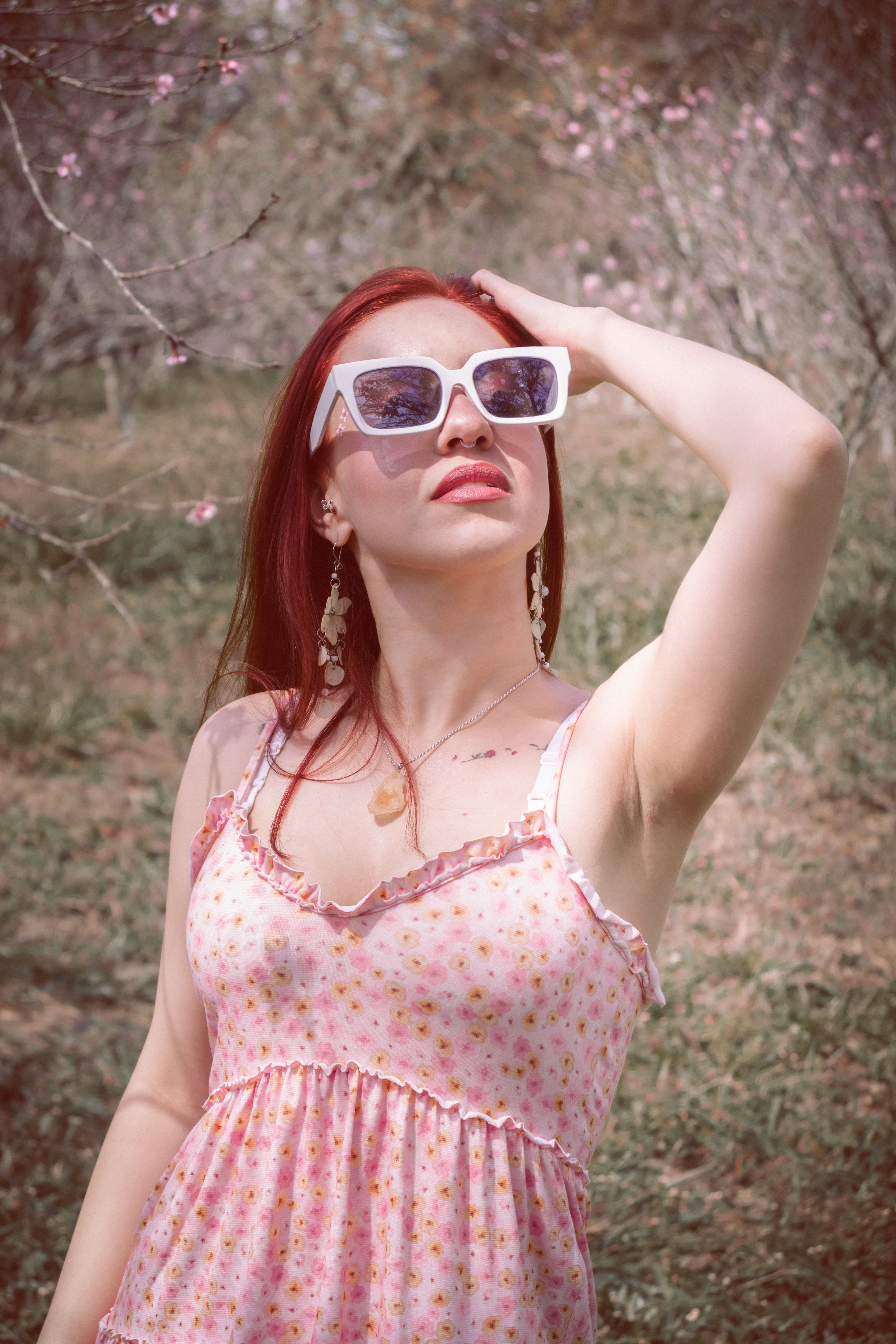 A woman with red hair and sunglasses standing in a field · Free Stock Photo