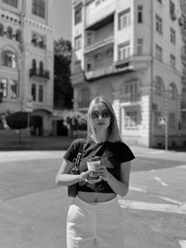 Stylish woman with coffee strolling in a chic urban setting.