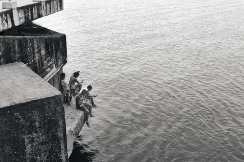 Free A group of children sit on a concrete structure overlooking the sea in Tumaco, Colombia. Stock Photo
