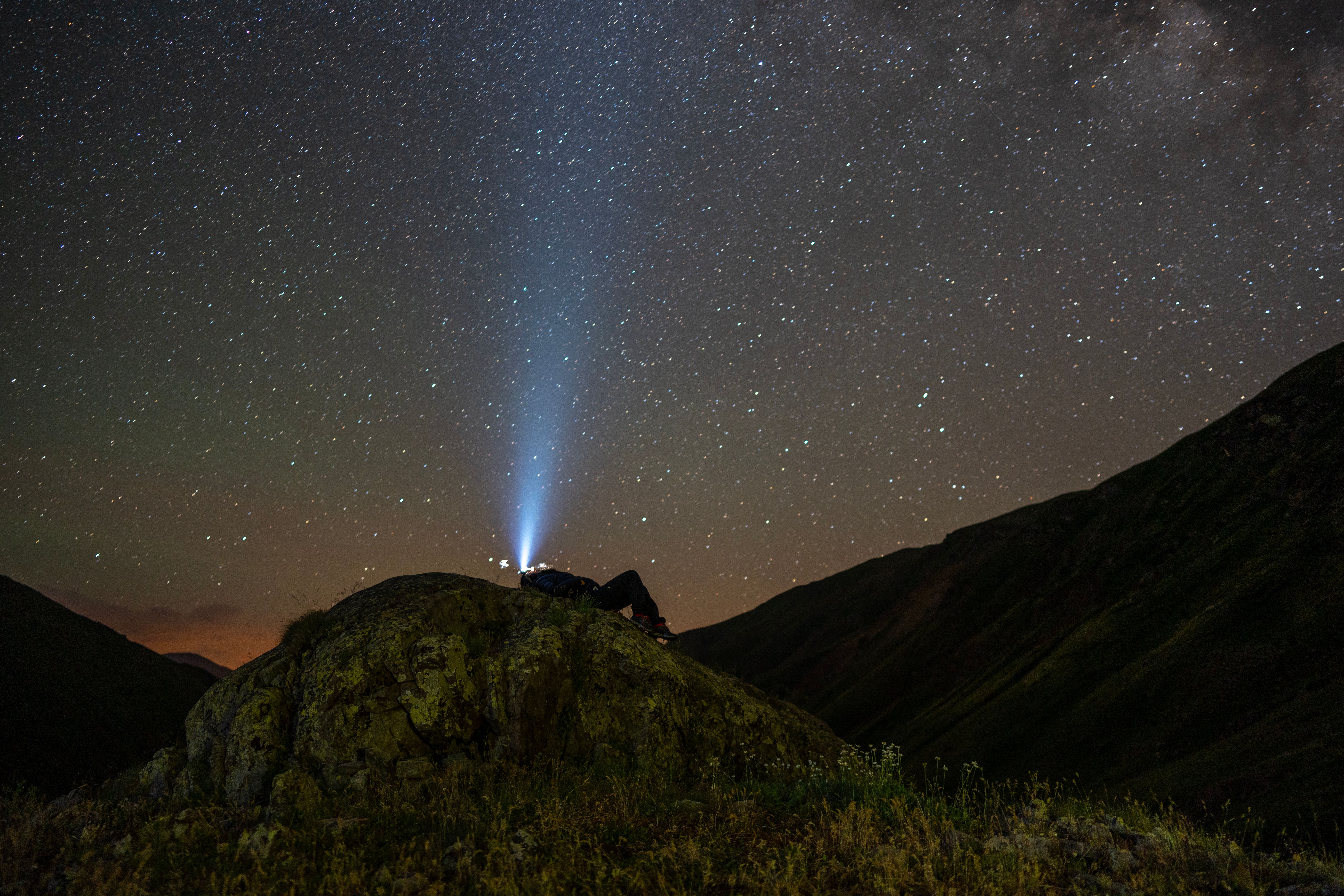 Stunning starry night sky over rocky mountains in İspir, Turkey, featuring Milky Way and flashlight beam.