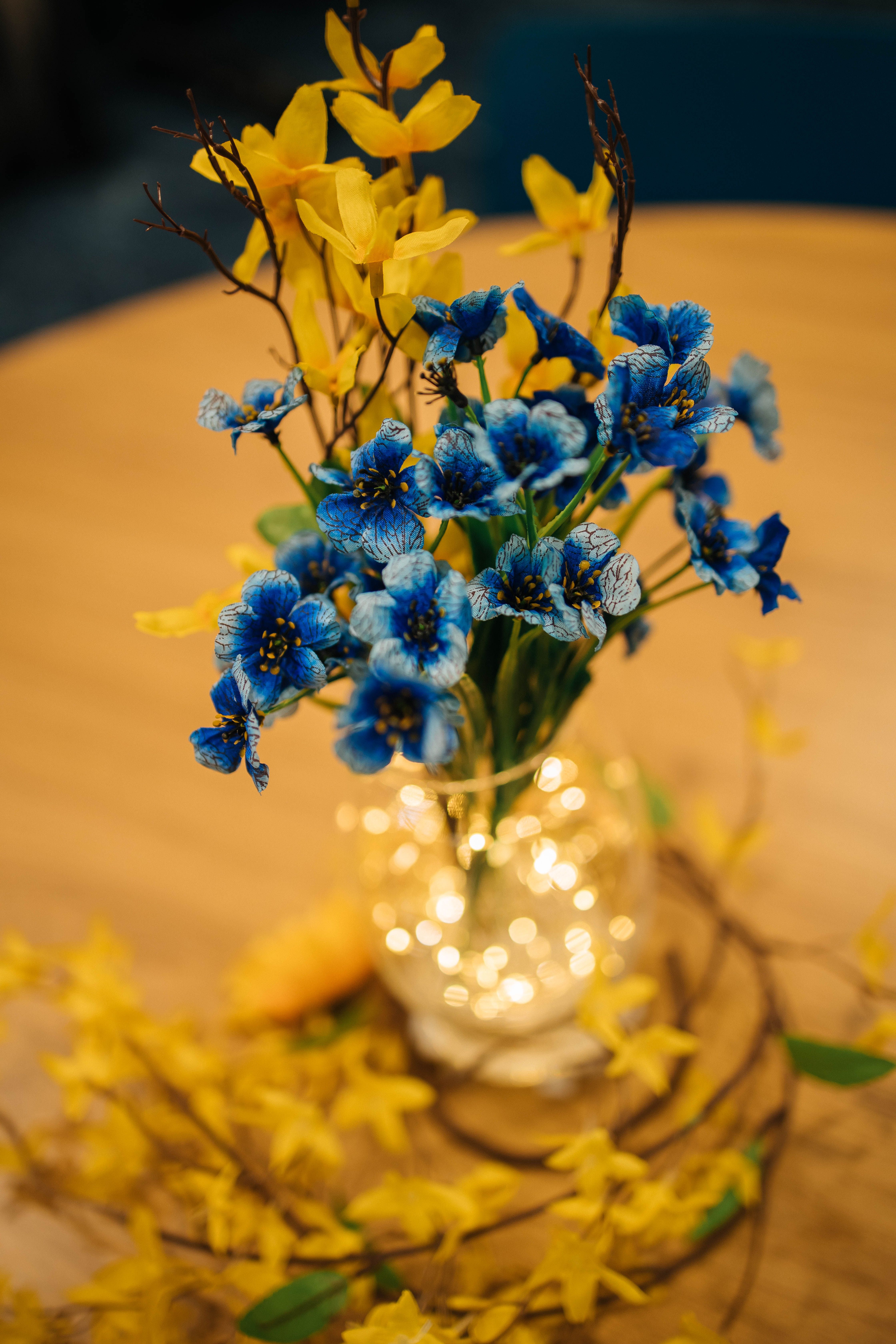 A vase with blue and yellow flowers on top of a table · Free Stock Photo