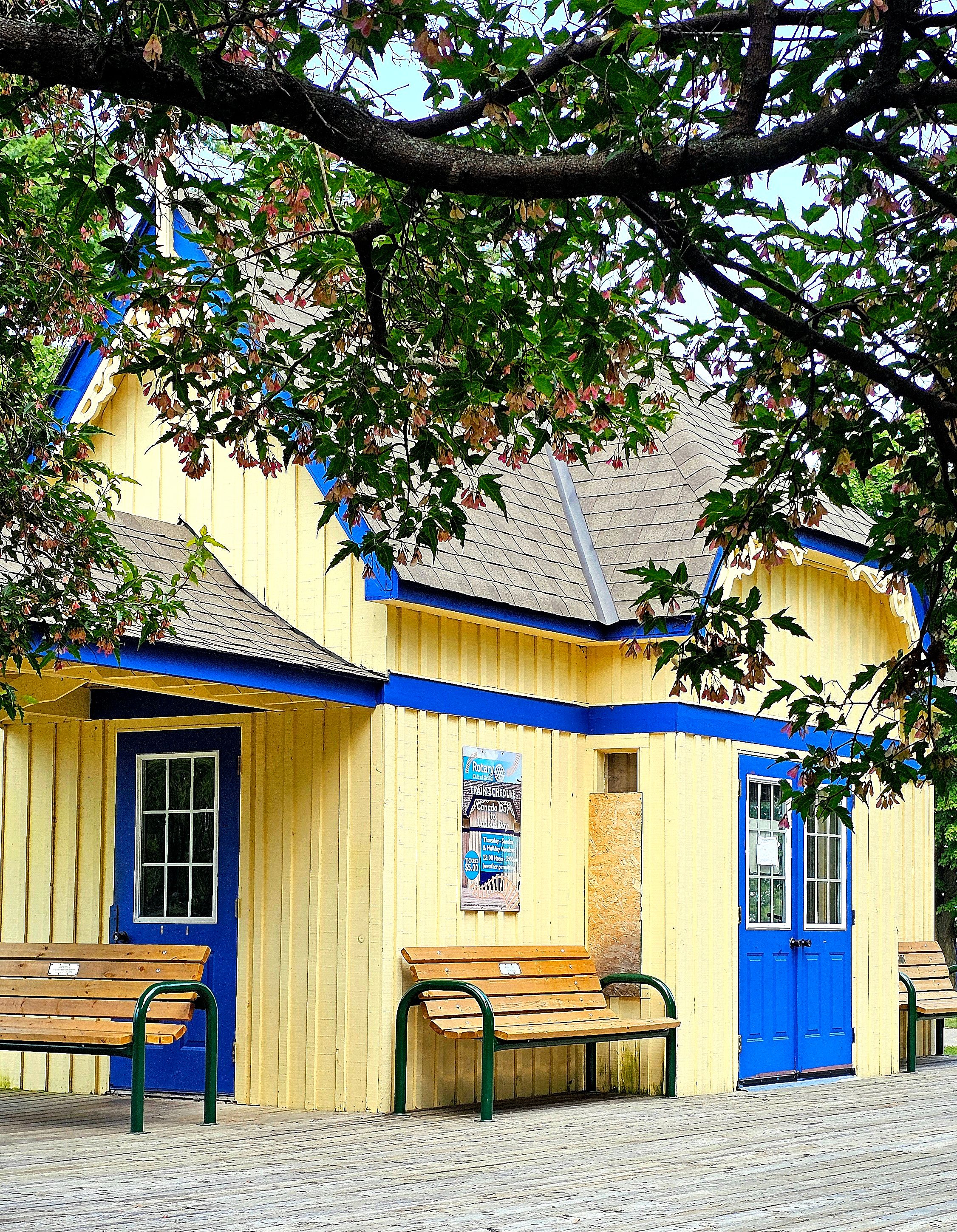 A yellow building with two benches and a tree · Free Stock Photo
