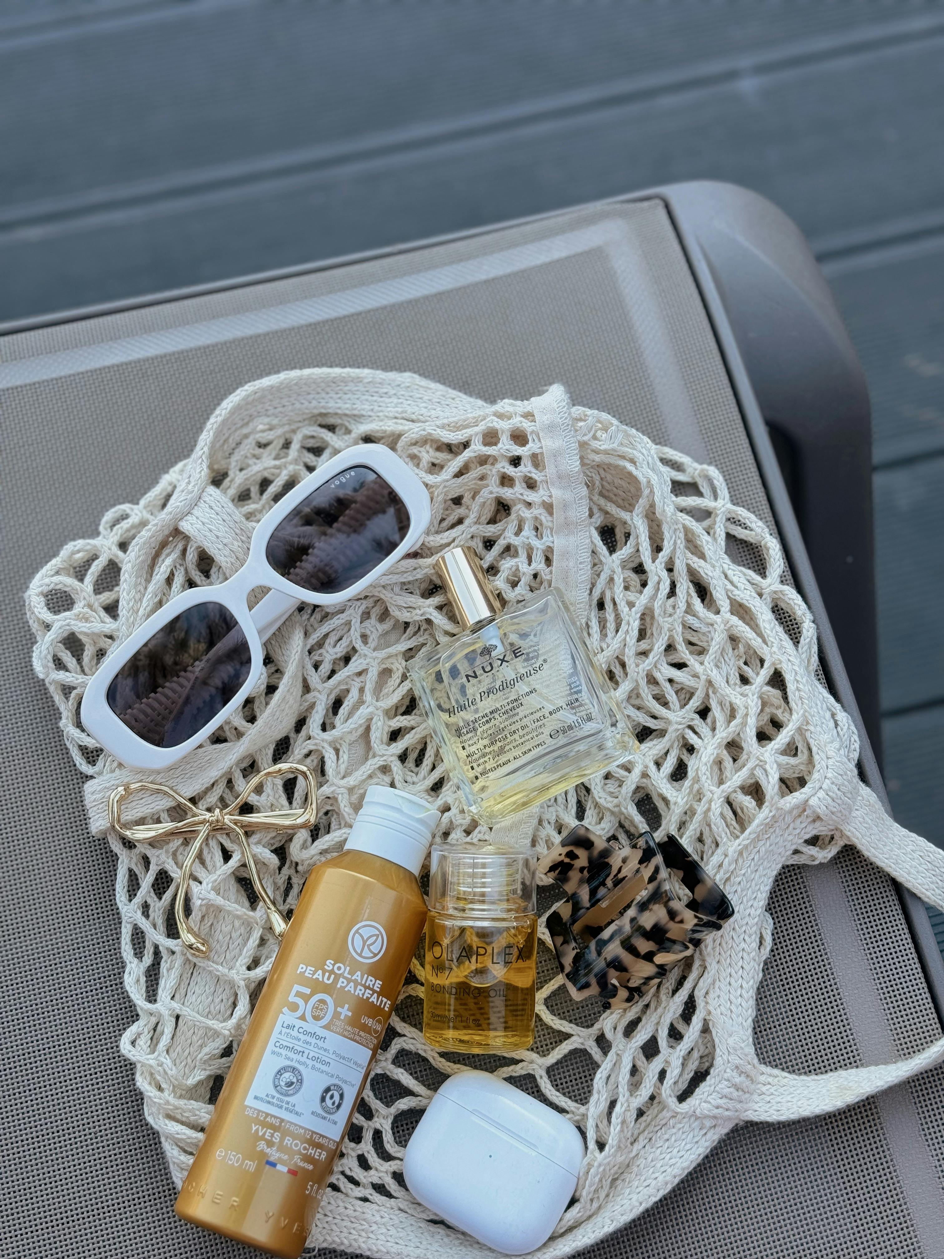 Beach essentials including sunscreen, sunglasses, and accessories on a lounge chair in Alaçatı.