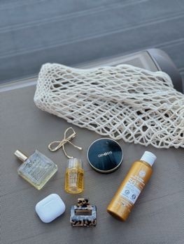 Elegant summer essentials including net bag and perfume laid out in a flat lay arrangement.