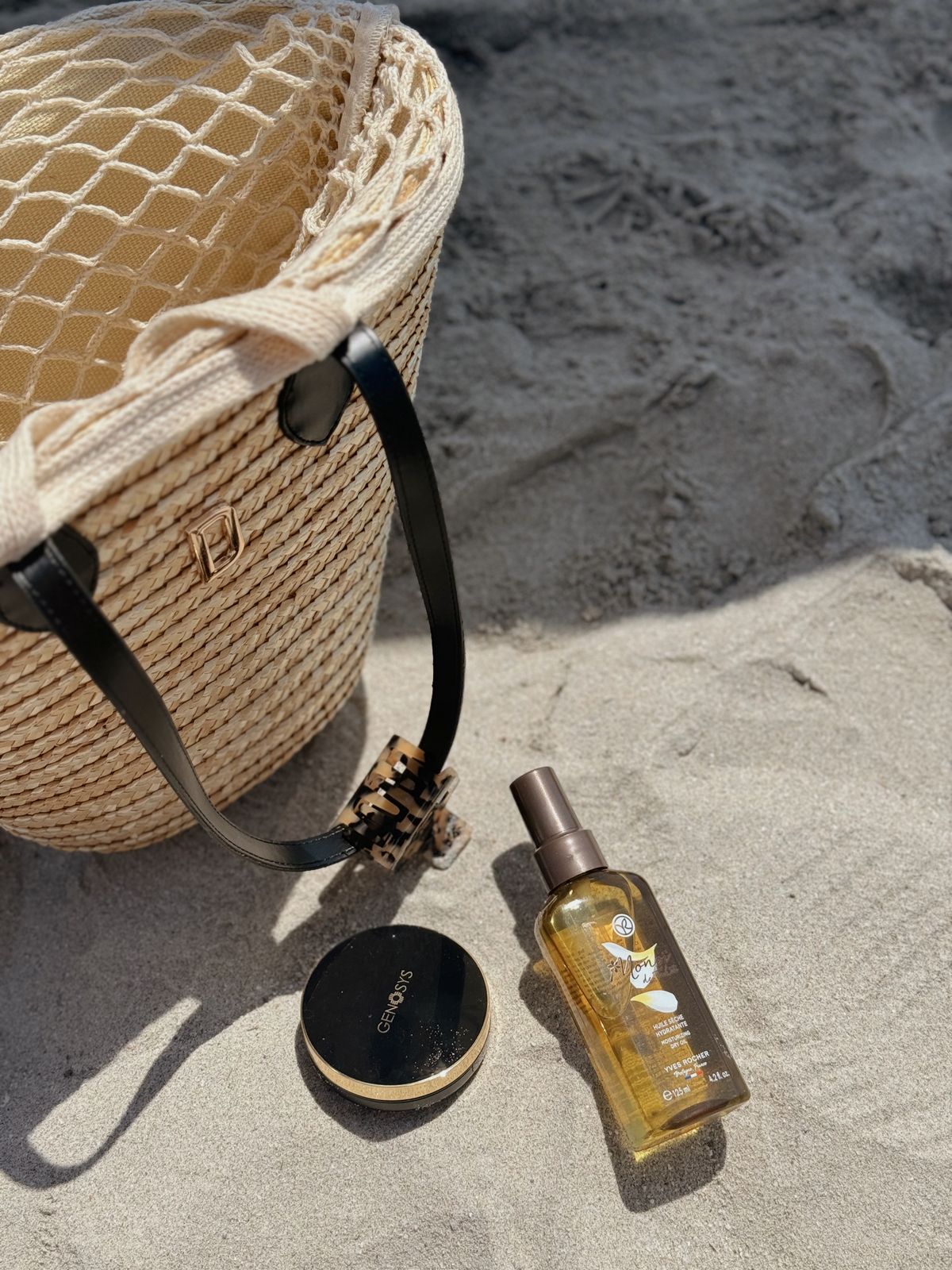 A raffia beach bag with sunscreen, lotion and the long slow day at the coast