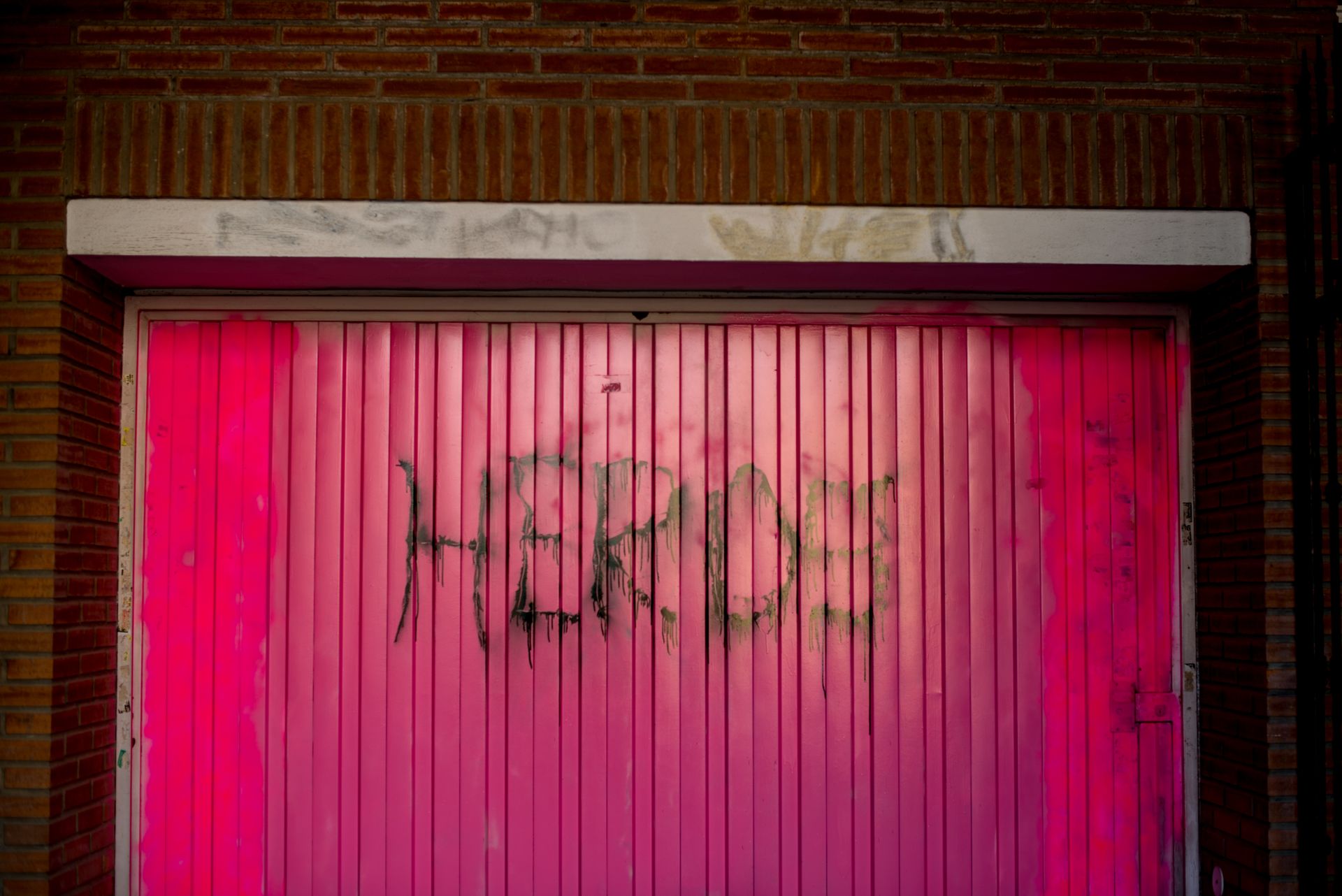 A vibrant pink garage door with graffiti in an urban area, exuding a rustic and retro vibe.