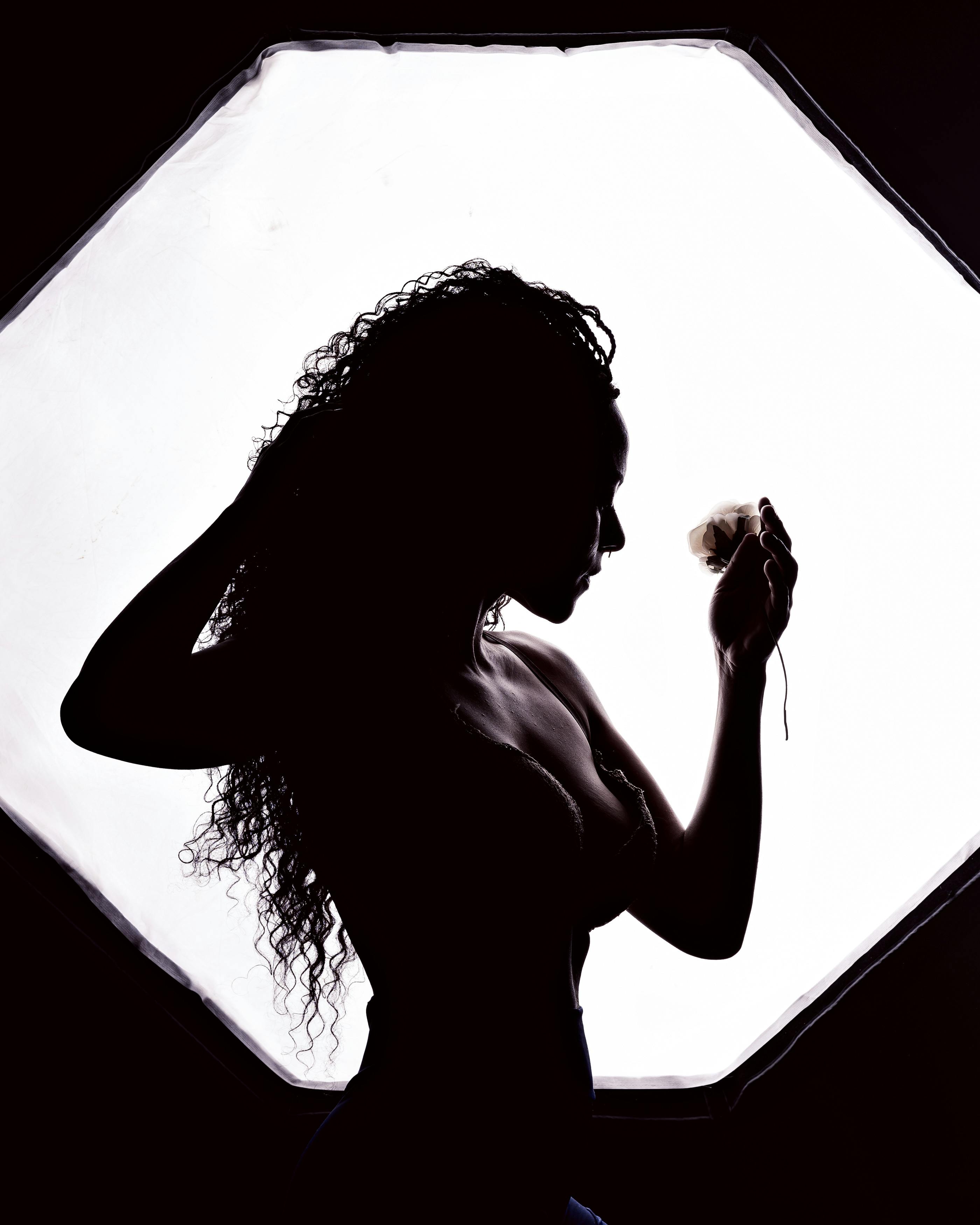 Artistic silhouette of a woman posing gracefully with bright studio backlight.