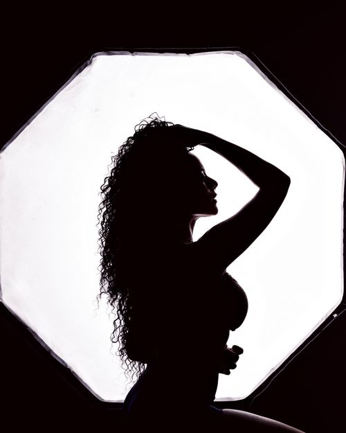 Free Silhouette of a woman against a bright light creates an artistic and mysterious portrait. Stock Photo