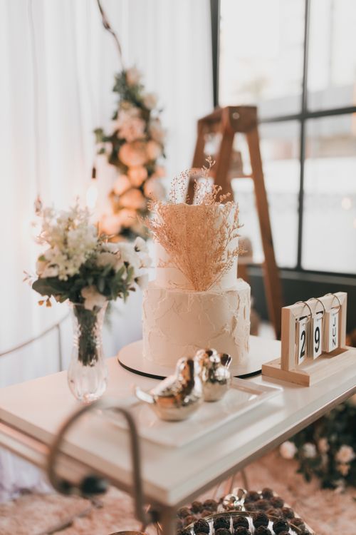 Free Elegant white wedding cake with floral decor on a stylish table indoors. Stock Photo