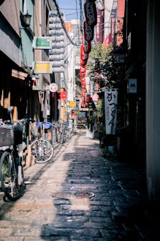 在日本大阪一条空荡荡的城市小巷里，可以看到自行车、狭窄的建筑和鹅卵石上的轻松游乐设施