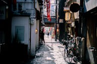 在日本大坂的一条狭窄小巷里，设有自行车、步行和传统标志，捕捉了城市街头生活的瞬间