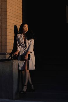 日落时分，一位时尚女子身着优雅服装在户外摆姿势