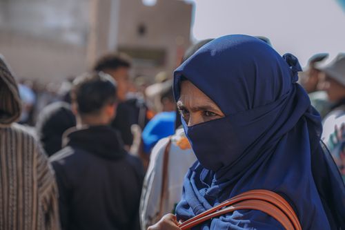 Free A woman in a blue hijab amidst a bustling crowd in Imsouane, Morocco. Stock Photo