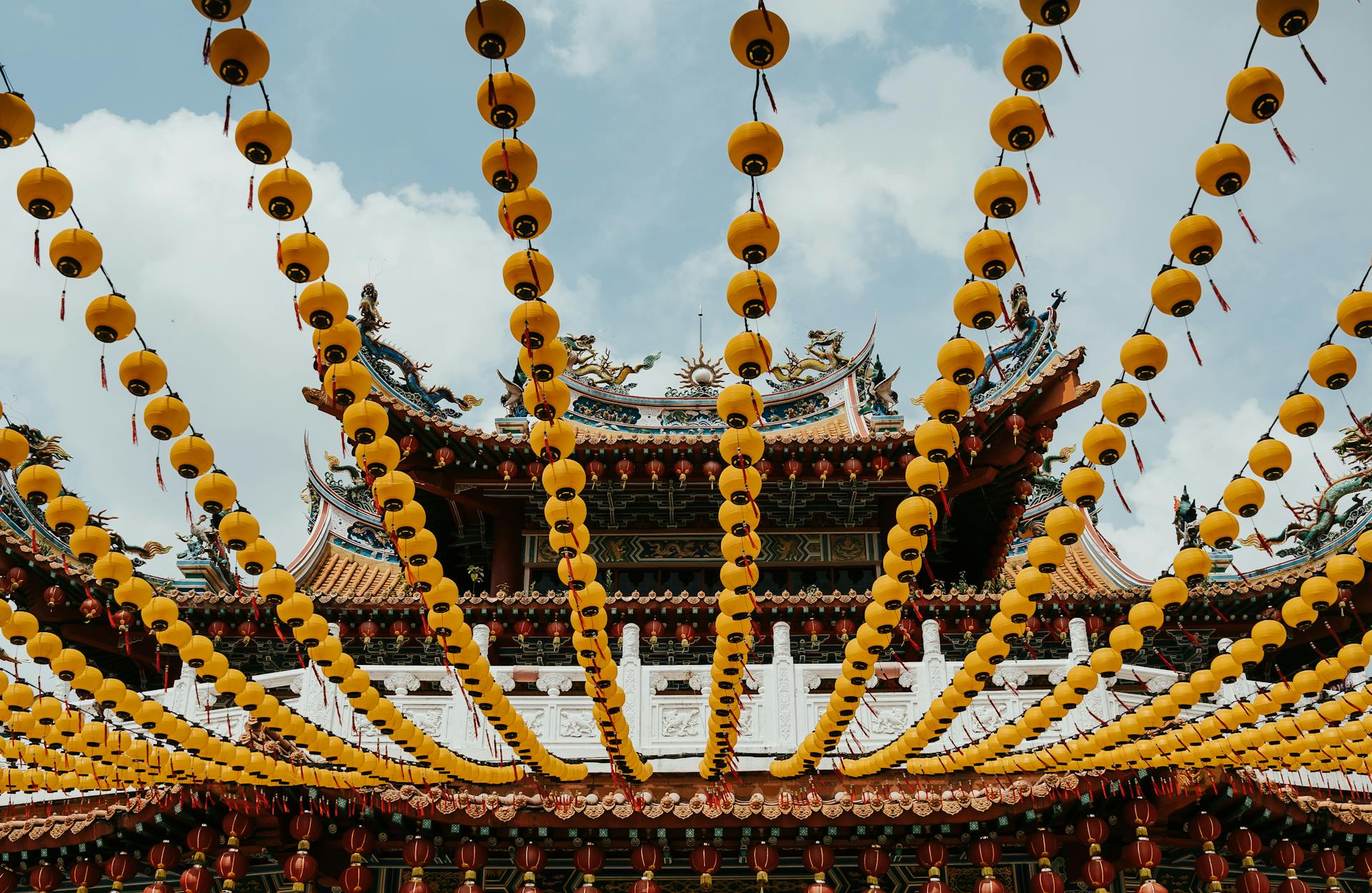 Colorful Chinese temple adorned with vibrant yellow lanterns under a clear sky.