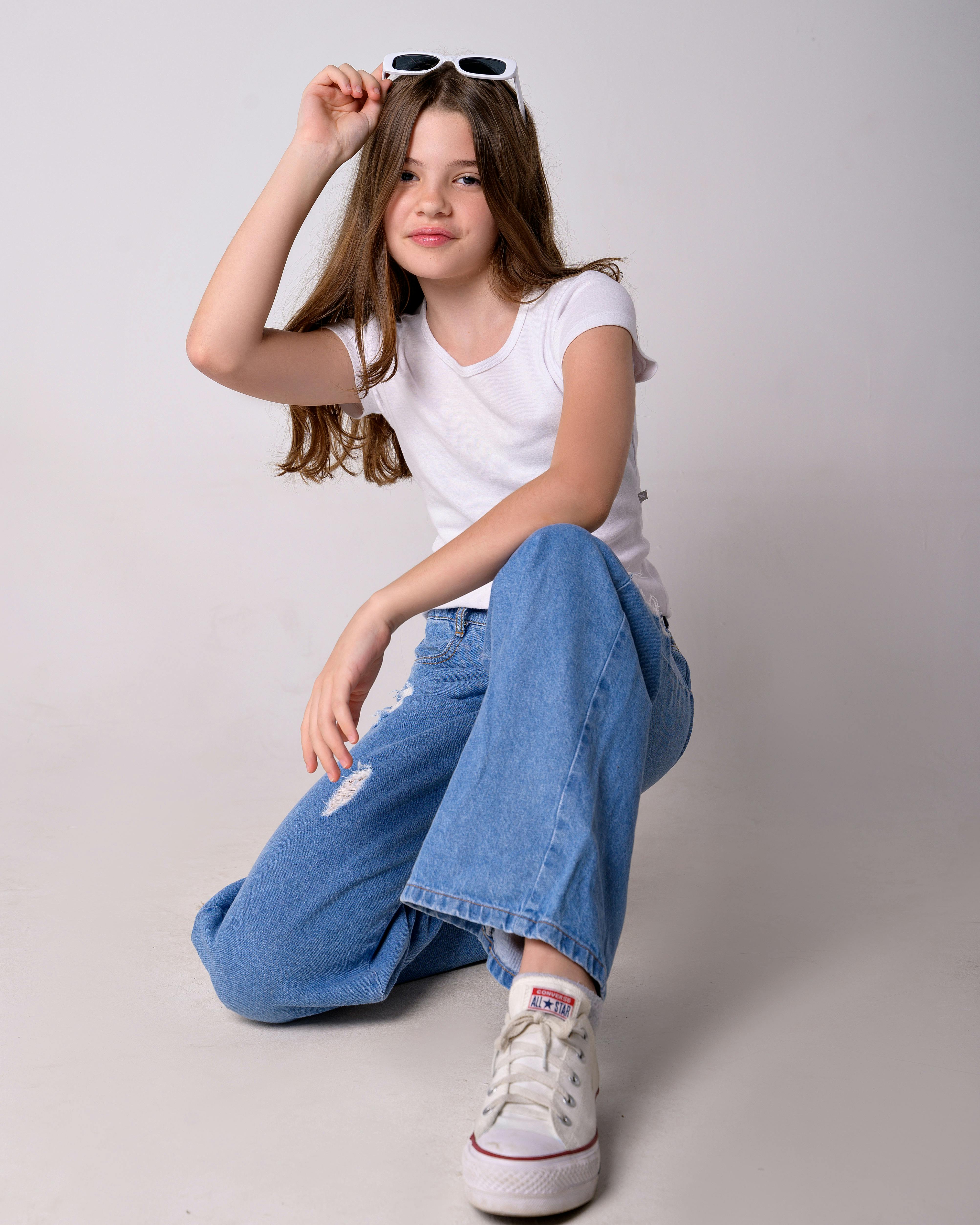 a young girl wearing white t shirt and jeans