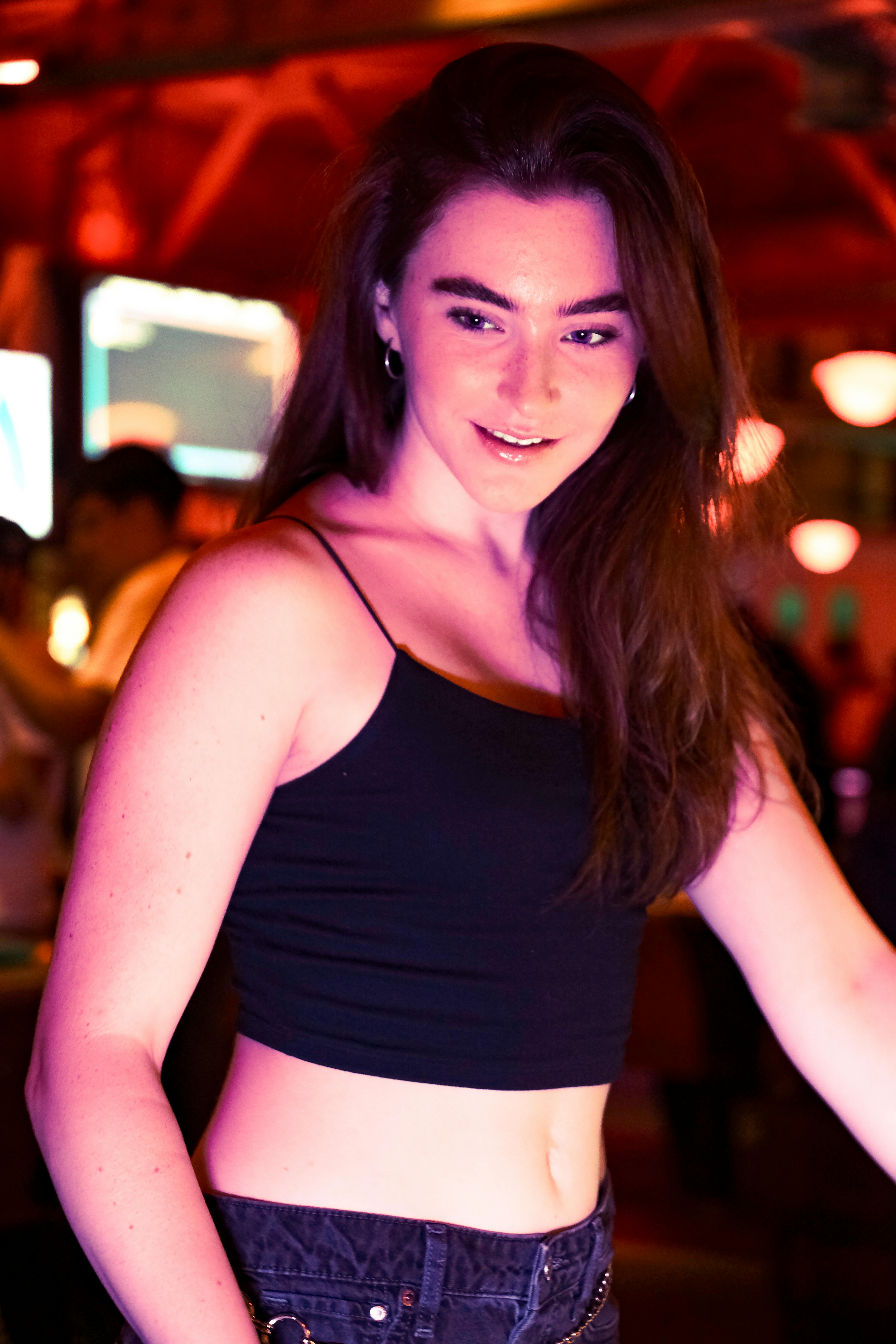 a woman in a black top and jeans standing in a bar