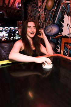 Young woman playing air hockey in a vibrant arcade setting, enjoying a night out.