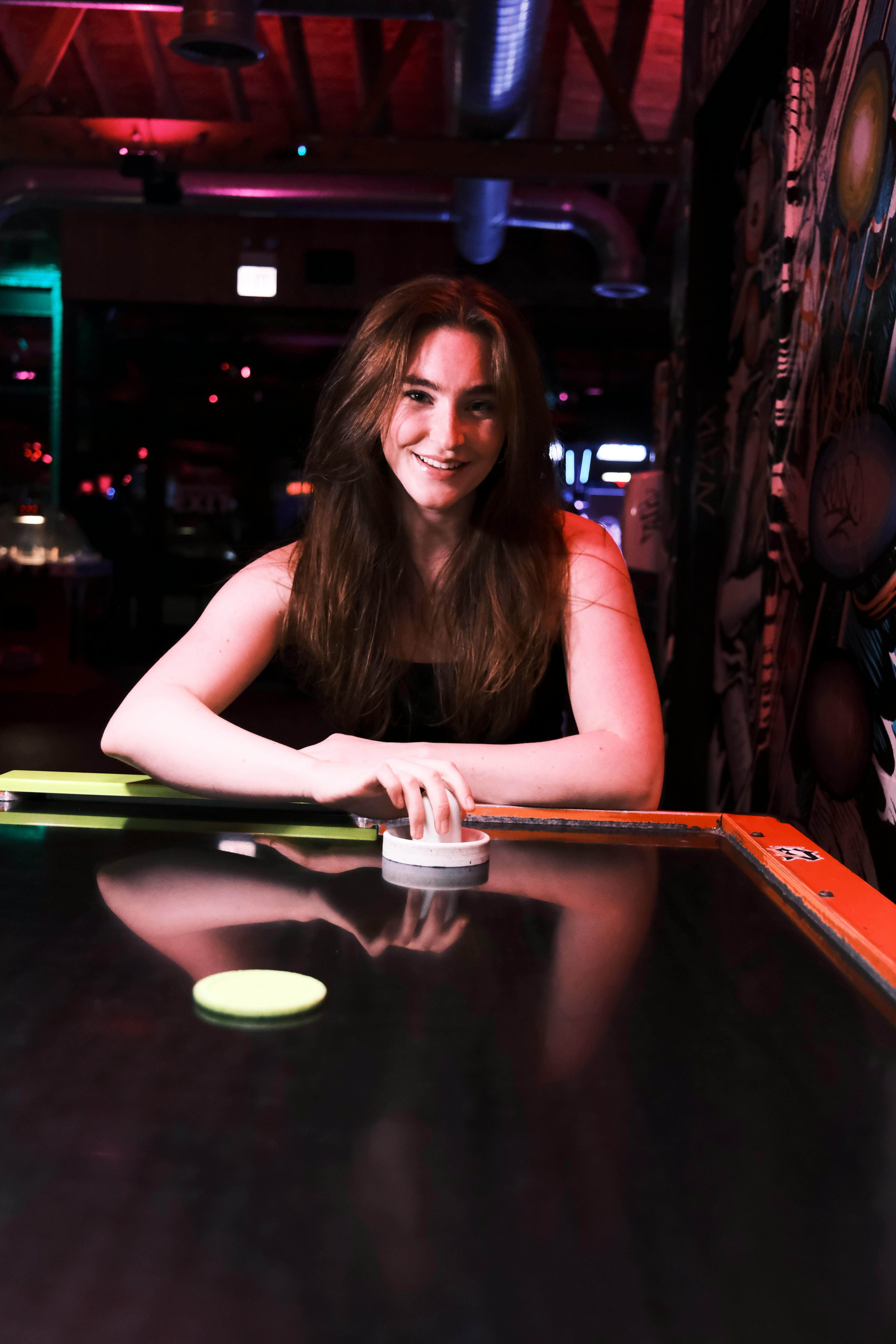 a woman sitting at a table with a pool table