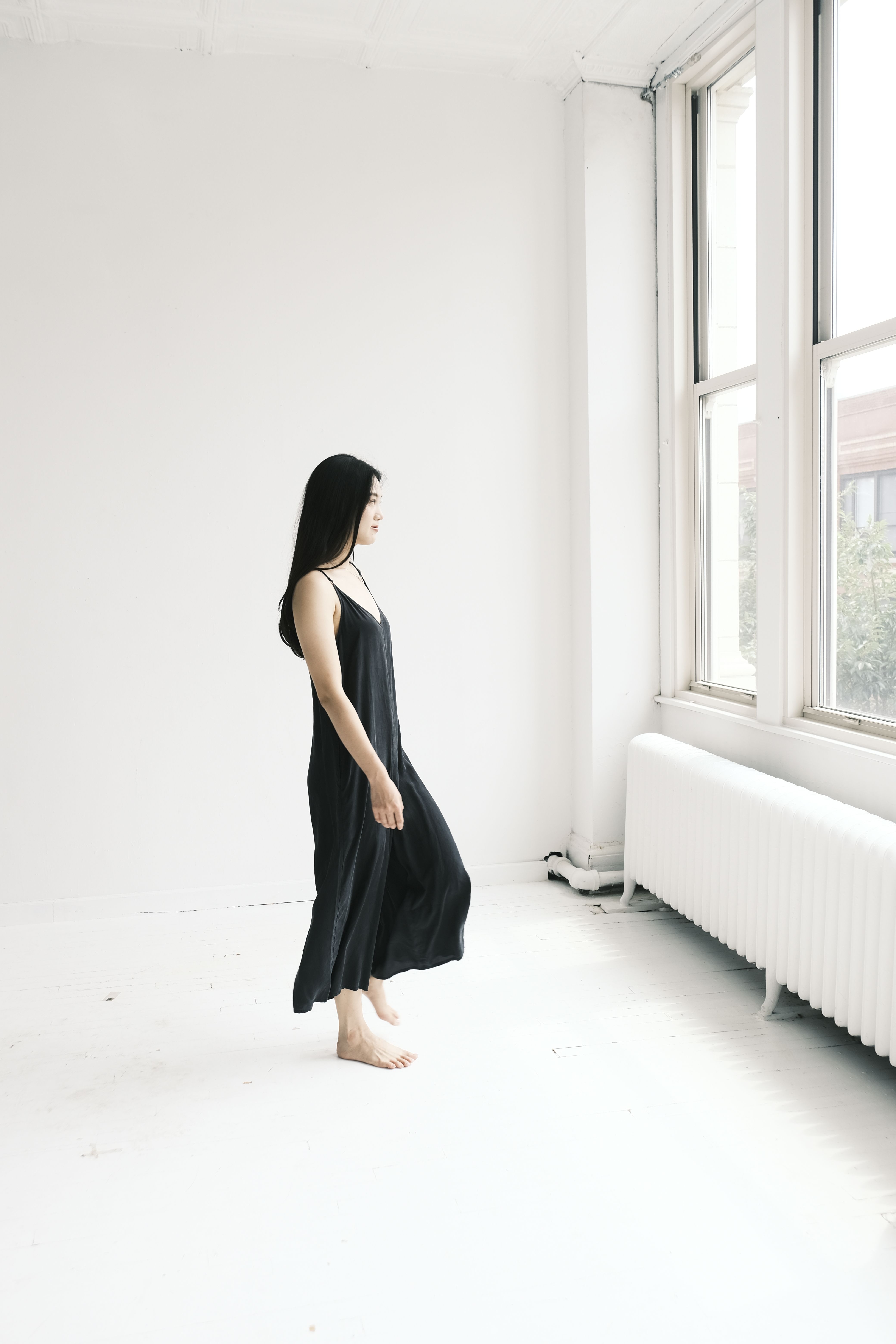 A woman in a black dress standing in front of a window · Free Stock Photo