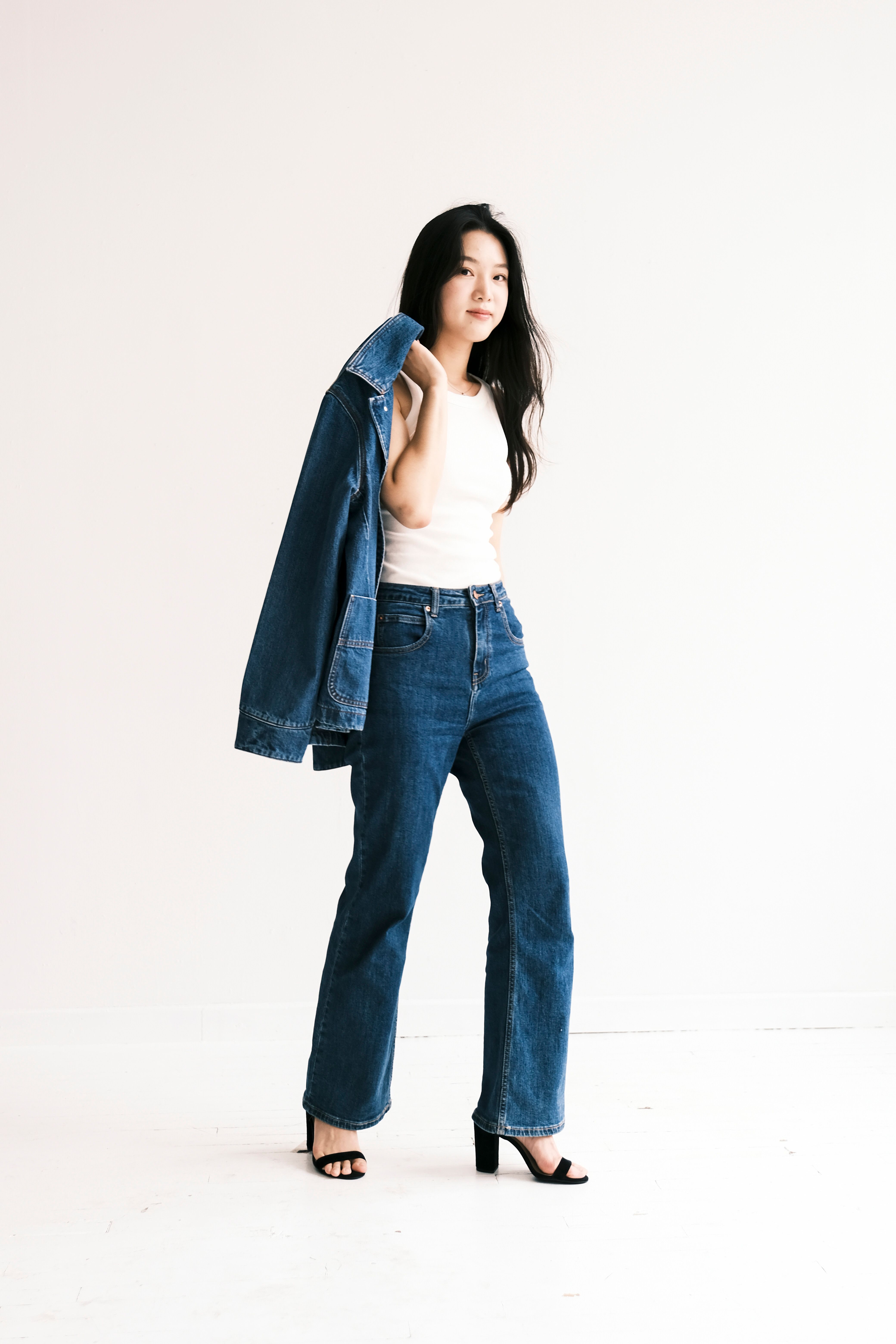 Stylish woman posing in denim outfit against a light studio backdrop.