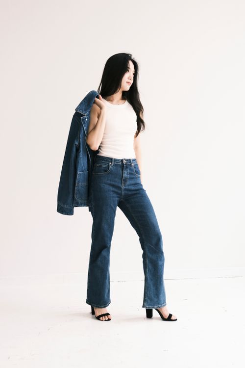Free Young woman in fashionable denim holding jacket, posing confidently against a neutral backdrop. Stock Photo